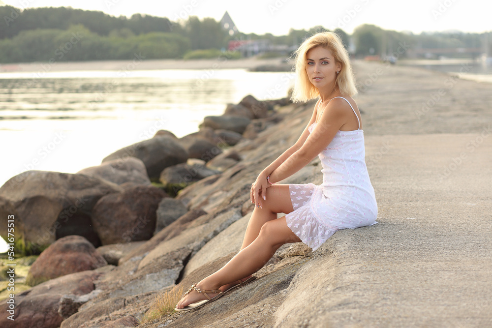 young woman by the sea in a white dress