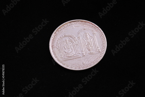 Close of a silver coin engraved with images of lord Venkateshwara and Ambal photo