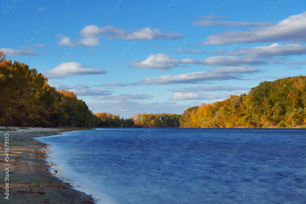 beautiful nature, autumn landscape - river and forest with bright sunlight, shadows from clouds on trees, yellow autumn color of leaves beautiful nature, autumn landscape - river and forest with bright sunlight, shadows from clouds on trees, yellow autumn color of leaves
