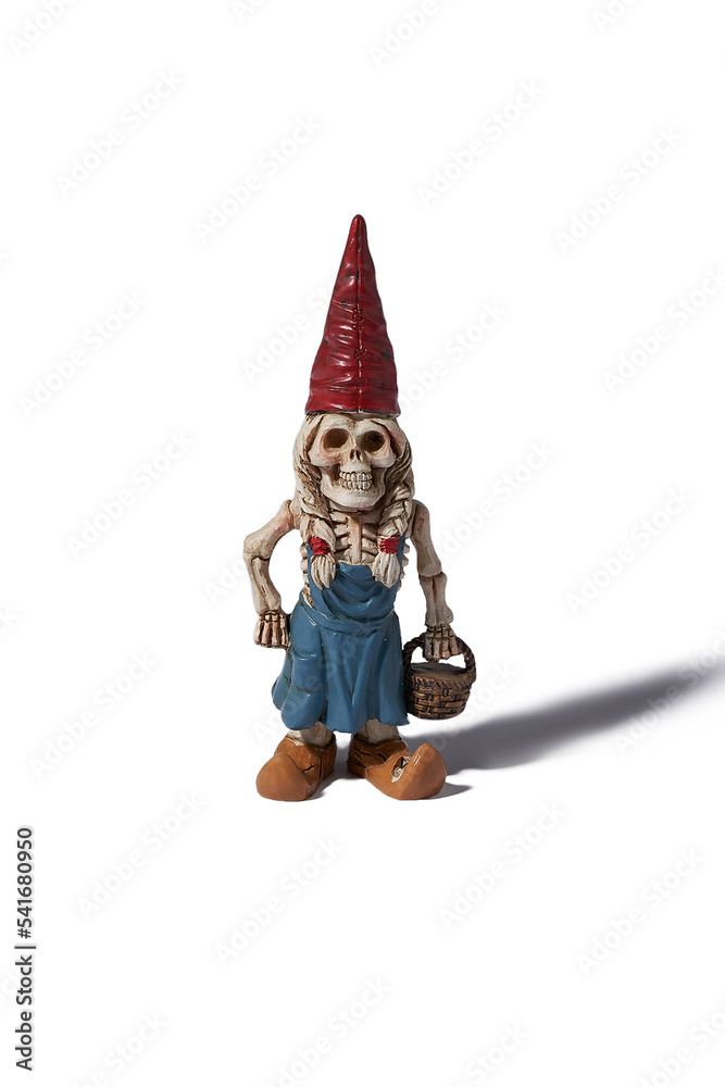 Detail front shot of a designer figurine of a skeleton of a dwarf woman in a red hat and a blue dress with a basket in hand. The original handmade statuette is isolated on the white background. Detail front shot of a designer figurine of a skeleton of a dwarf woman in a red hat and a blue dress with a basket in hand. The original handmade statuette is isolated on the white background.