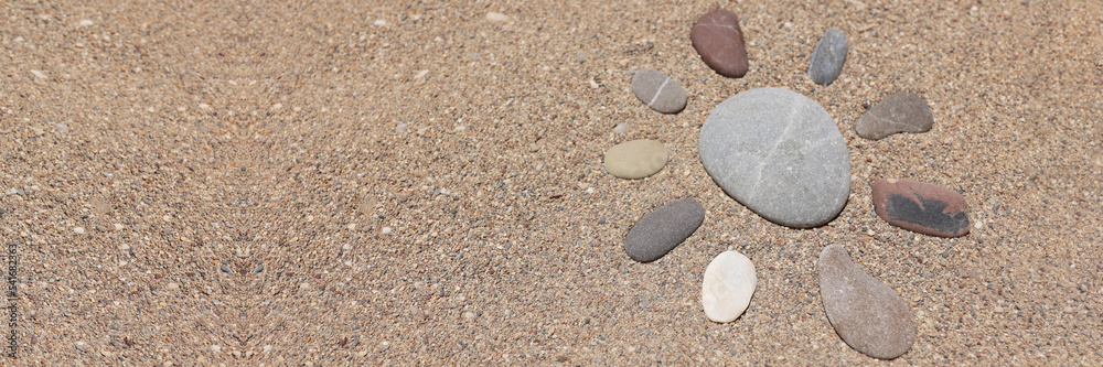 Stones put in form of sun, sandstone on sandy beach, hot sand, holiday time Stones put in form of sun, sandstone on sandy beach, hot sand, holiday time