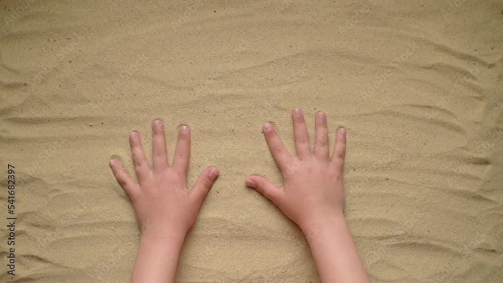 the child puts his brushes on the sand to leave footprints. slow motion video the child puts his brushes on the sand to leave footprints. slow motion video