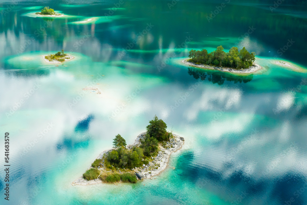 Unique islands with trees on a lake, turquoise water and clouds reflect, aerial view. 
