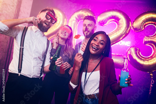 Multiracial friends celebrating new years eve with party props in the club