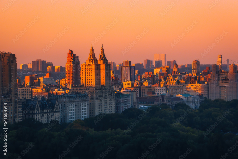 Fototapeta premium Aerial view of the Central park in Manhattan, New York with golf fields and tall skyscrapers surrounding the park. Sunset view.