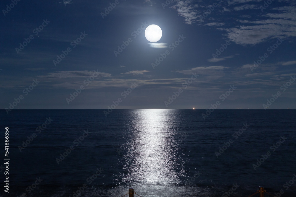 雲の上の満月が海を輝かせる