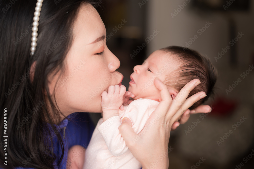 lifestyle shot on young and happy Asian Chinese woman holding tenderly her adorable newborn baby girl in her arms in mother and daughter love and care concept lifestyle shot on young and happy Asian Chinese woman holding tenderly her adorable newborn baby girl in her arms in mother and daughter love and care concept