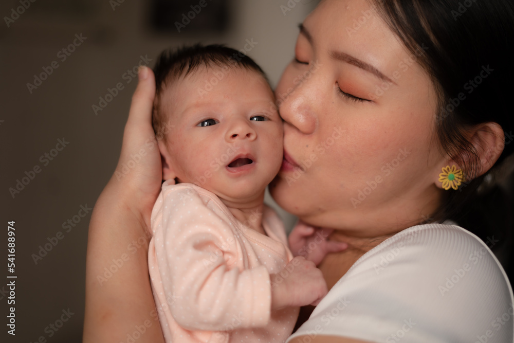 lifestyle shot on young and happy Asian Chinese woman holding tenderly her adorable newborn baby girl in her arms in mother and daughter love and care concept lifestyle shot on young and happy Asian Chinese woman holding tenderly her adorable newborn baby girl in her arms in mother and daughter love and care concept