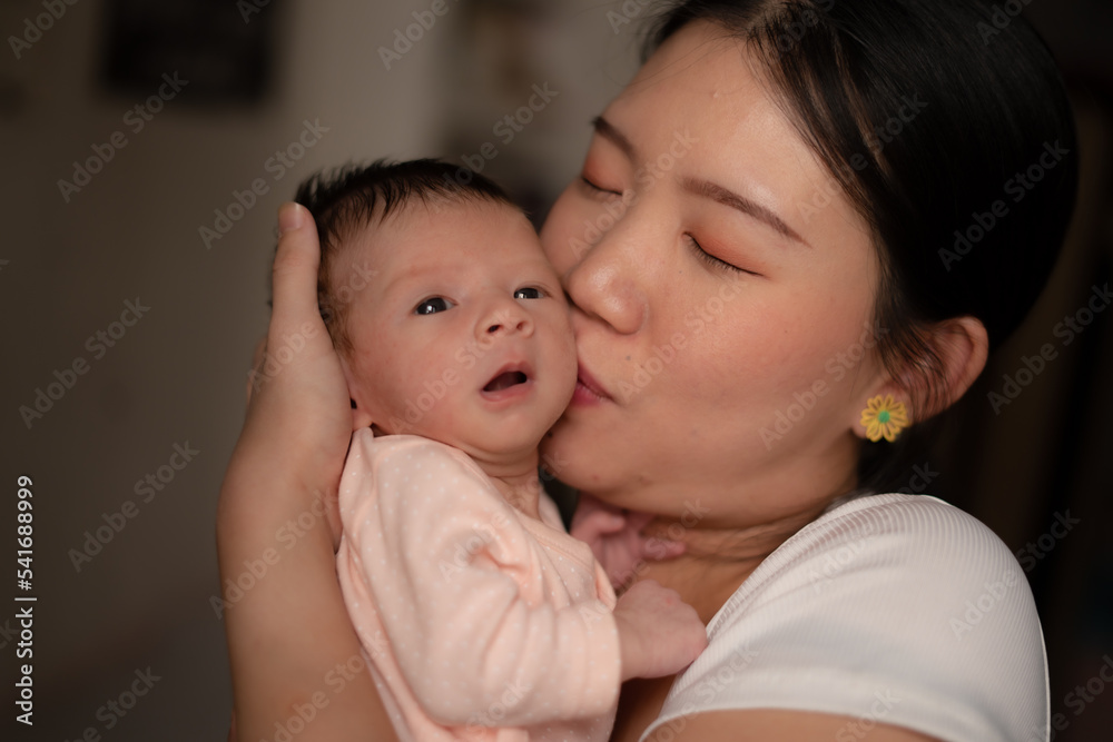 lifestyle shot on young and happy Asian Chinese woman holding tenderly her adorable newborn baby girl in her arms in mother and daughter love and care concept lifestyle shot on young and happy Asian Chinese woman holding tenderly her adorable newborn baby girl in her arms in mother and daughter love and care concept