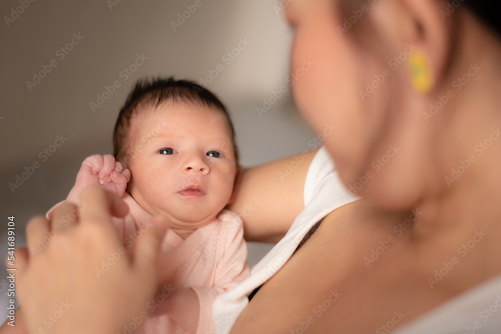 lifestyle shot on young and happy Asian Chinese woman holding tenderly her adorable newborn baby girl in her arms in mother and daughter love and care concept lifestyle shot on young and happy Asian Chinese woman holding tenderly her adorable newborn baby girl in her arms in mother and daughter love and care concept