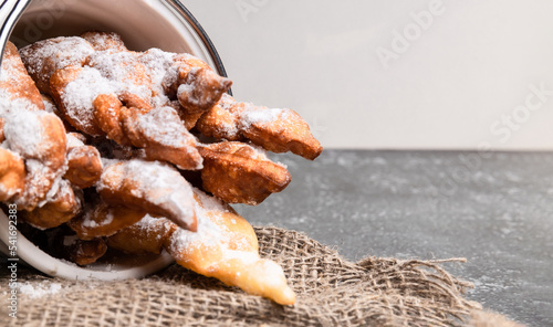 russian traditional dish - Brushwood hvorost. cookies with sugar powder on a white bucket. selective focus photo