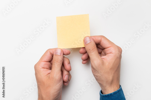 hands of an office worker hold colored stickers for notes on a white background, close-up