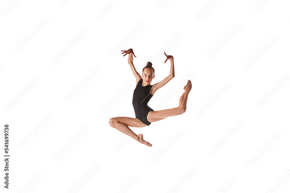 Emotions in motion. Portrait of junior gymnast in black sport swimsuit doing gymnastics excercises isolated over white background. Sport, skills, achievements