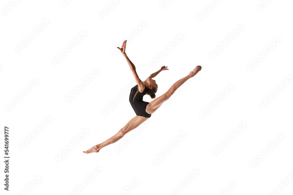 Twine in jump. Portrait of junior gymnast in black sport swimsuit doing gymnastics excercises isolated over white background. Sport, skills, achievements
