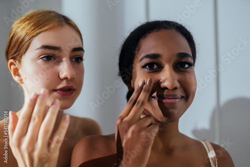 Close-up of two young women applying cream to their face