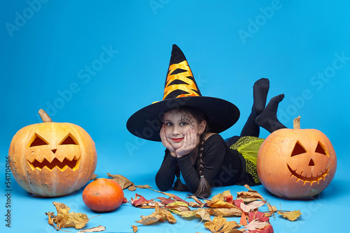 portrait of a charming little girl in a witch costume, Jack's lamps are standing around. the concept of the heluin holiday photo