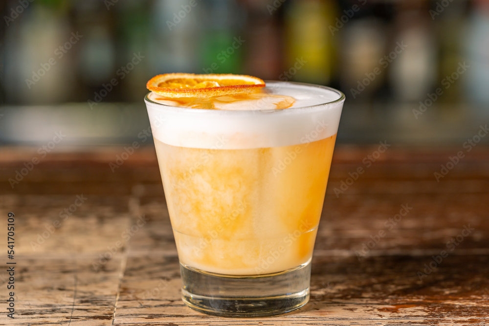 Vanilla Sour cocktail with egg white and lemon juice on the bar. Vanilla Sour cocktail with egg white and lemon juice on the bar.