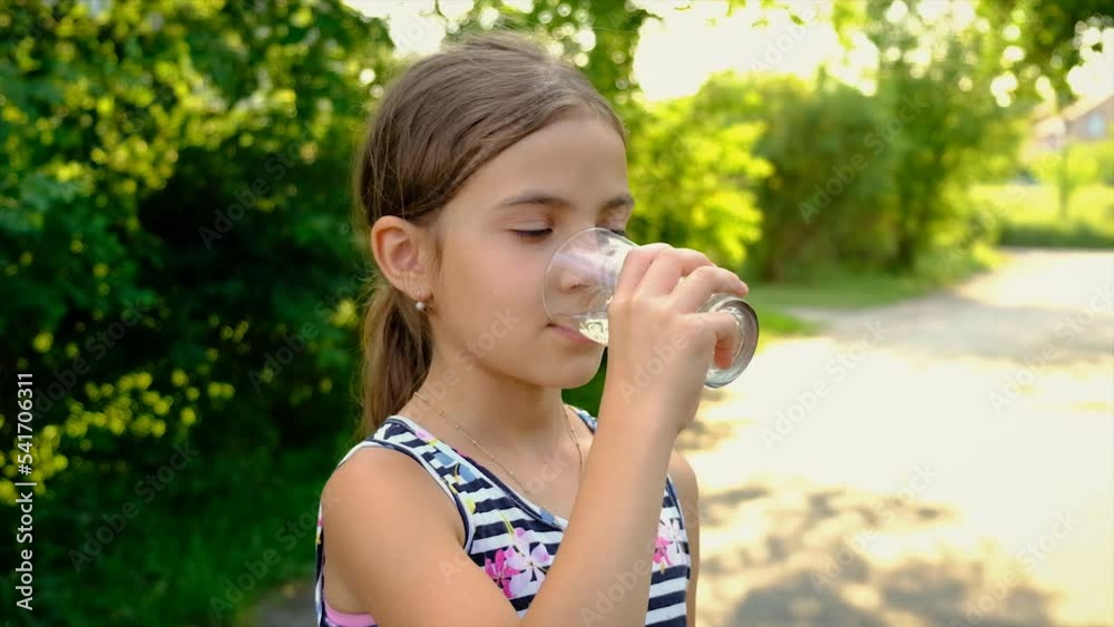 The child drinks water from a glass. Selective focus. The child drinks water from a glass. Selective focus.