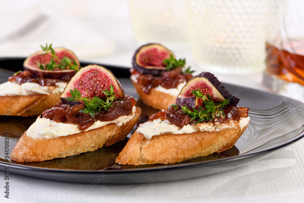 Set Bruschetta with figs and cheese, onion jam, fresh thyme, on grilled crusty bread. Perfect as an aperitif for a holiday or party. 