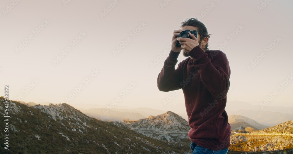 Man on mountain landscape at springtime travel photographing on vintage camera