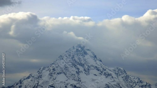 Timelapse, fast movement of clouds over the top of a snowy mountain