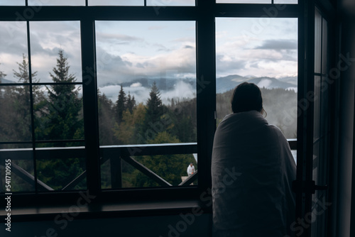 Young woman is looking through the window at the mountains