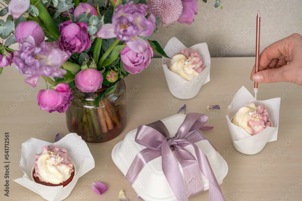 A beautiful bouquet and cupcakes lie on the pink table A beautiful bouquet and cupcakes lie on the pink table