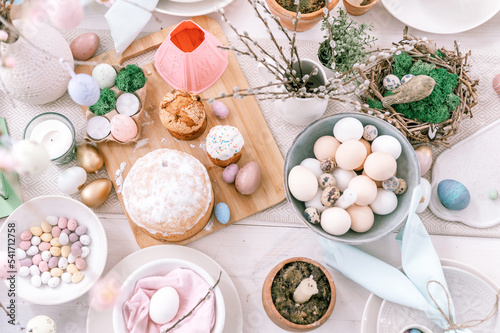 happy easter and spring holidays time. festive tablescape set decor. traditional dinner food easter eggs and baked cakes on table at home. willow sprig. pale pop pastel blue and pink color. top view