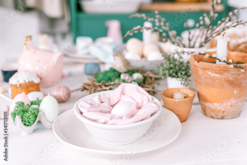 happy easter and spring holidays time. festive tablescape set decor. traditional dinner food easter eggs and baked cakes on table at home. rabbit and willow. pale pop pastel blue and pink color