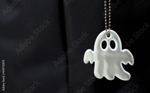 Key chain reflective in a ghost pattern form on black background, security sign to protect pedestrian visibility from vehicles on the road. Accessory essential for passerby to walk on the dark street