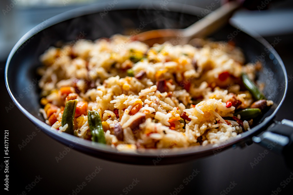 cooking tasty rice and vegetable mix with corn, pea, beans in pan on kitchen