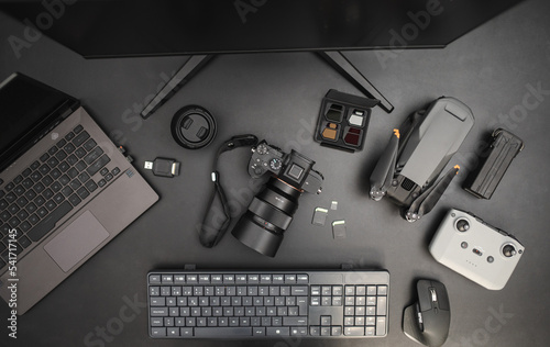 Workplace of photographer videographer with drone, camera, laptop, keyboard, computer, mouse. Top view on dark background