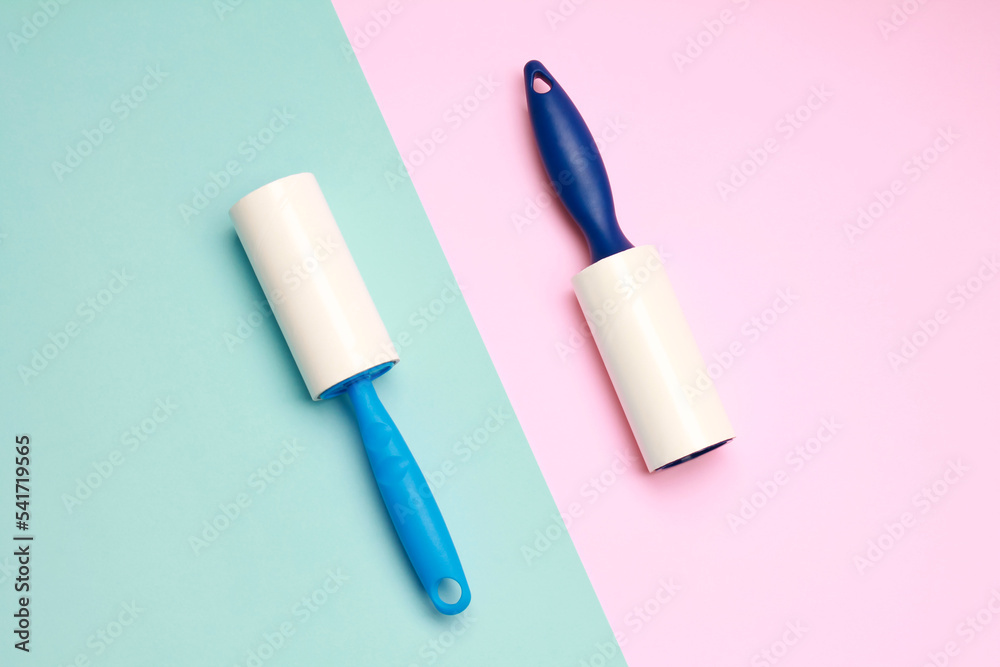 Cloth fabrics cleaner lint roller brush with paper roll blue grip on pink mint green color background. sticky roller, pet cat dog fur dust hair remover. Top view. Flat lay Cloth fabrics cleaner lint roller brush with paper roll blue grip on pink mint green color background. sticky roller, pet cat dog fur dust hair remover. Top view. Flat lay