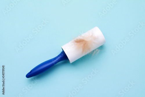 Cloth fabrics cleaner lint roller brush with paper roll blue grip on blue color background. sticky roller, pet cat dog fur dust hair remover. top view