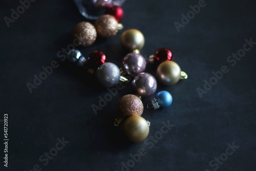 Glass with colorful Christmas baubles on dark background. Selective focus.