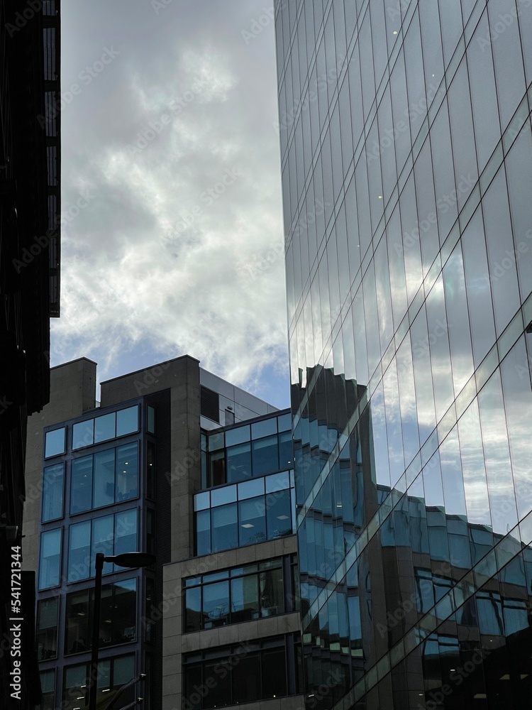 Looking up at modern buildings with a cloudy sky background. 