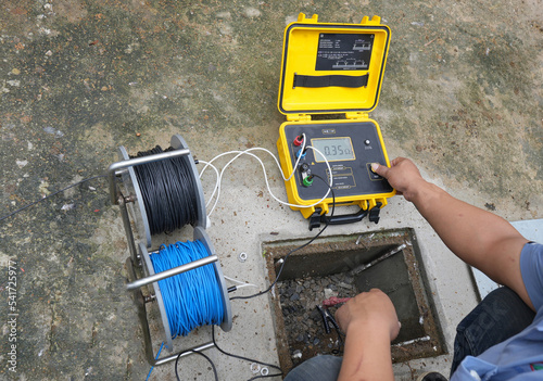 Technician is using a tester to measure electrical ground. Earth resistance tester.