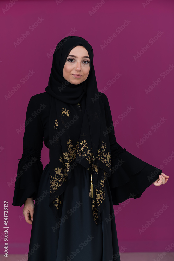 beautiful muslim woman in fashinable dress with hijab isolated on modern pink background representing concept of modern islam and ramadan kareem