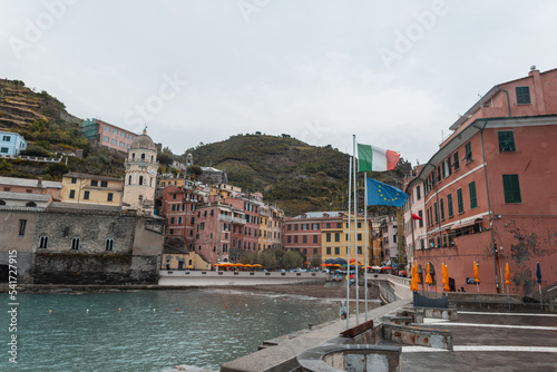 Beautiful village with old houses, narrow streets and the flag of italy on a rock near the sea in Vernazza, Italy © alones