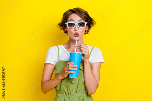 Portrait photo of impressed shocked woman bob brown hair wear 3d glasses specs poued lips drink soda nice film isolated on yellow color background photo
