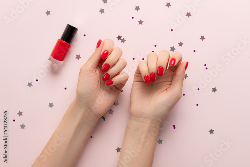 Fotografiet Beautiful female hand with red nail design on pastel background with confetti