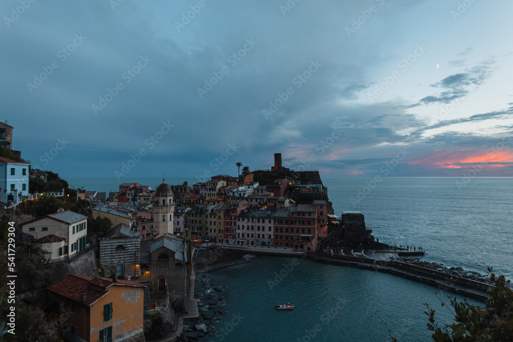 Beautiful vintage European fishing town with ancient buildings on a hill by the sea at sunset with clouds in Vernazza, Italy