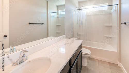 Panorama Sun flare Interior of a white bathroom with black bathroom fixtures and light gray tiles flooring