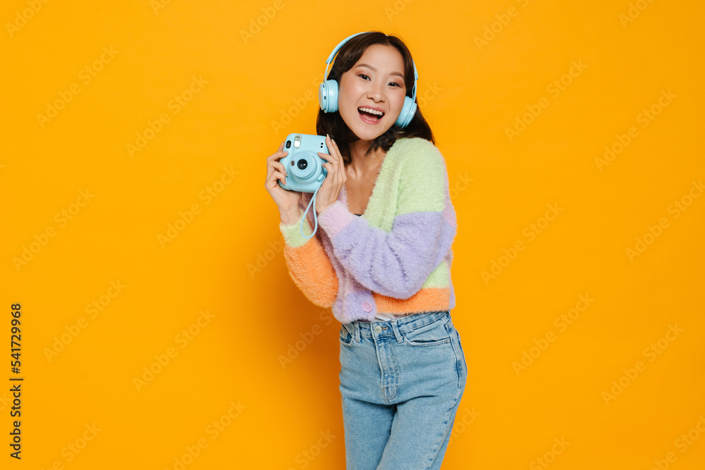 Asian young woman in headphones posing with instant camera Asian young woman in headphones posing with instant camera