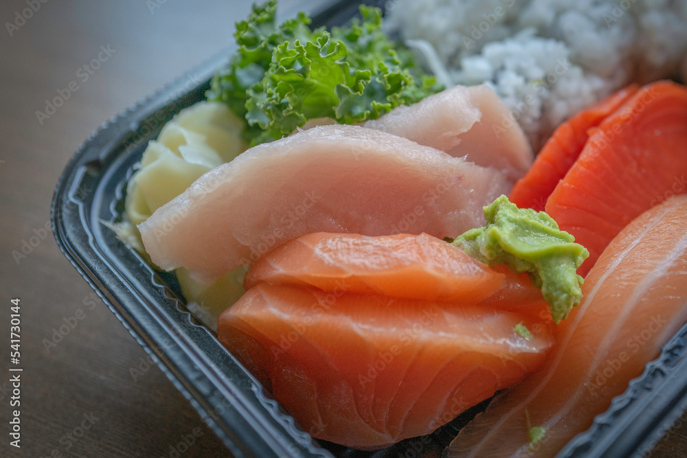 Sushi sashimi Japanese food takeout with yellow tail fish, salmon, California roll with rice, wasabi, ginger, and kale Sushi sashimi Japanese food takeout with yellow tail fish, salmon, California roll with rice, wasabi, ginger, and kale