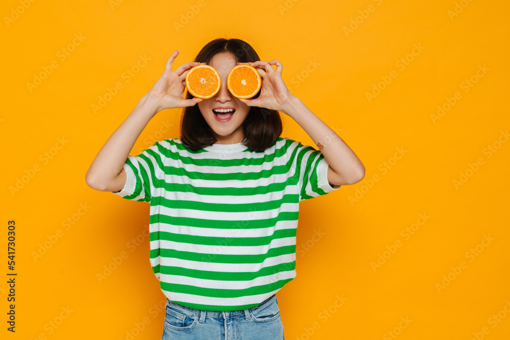 Asian young woman wearing stripped t-shirt smiling while holding orange Asian young woman wearing stripped t-shirt smiling while holding orange