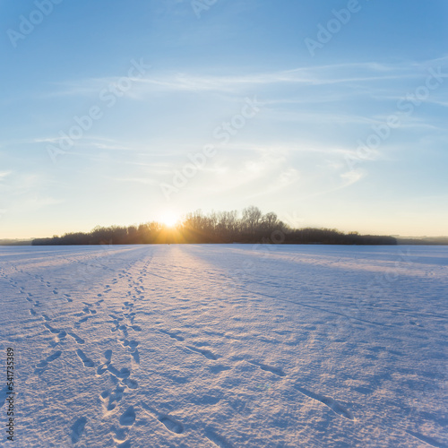frozen lake in snow and ice in light of evening sun  winter sunset background