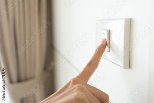 Fotografia close up hand of woman turning off light switch in a home.