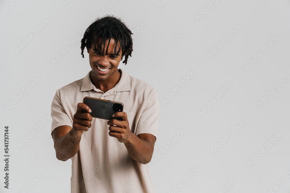 Excited young african man playing games on mobile phone isolated Excited young african man playing games on mobile phone isolated