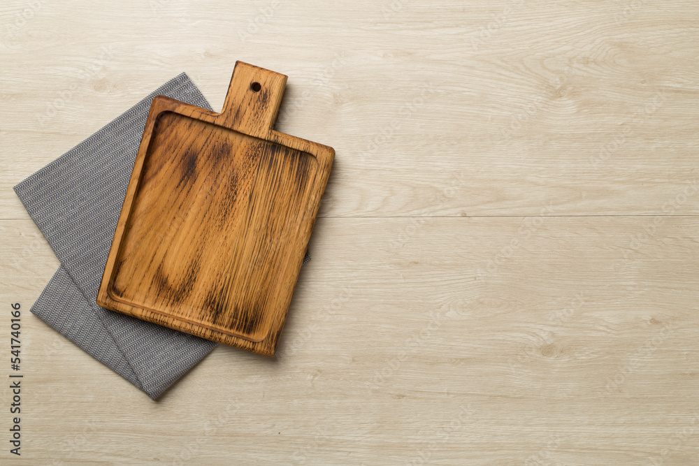 Cutting board with towel on wooden background, top view Cutting board with towel on wooden background, top view